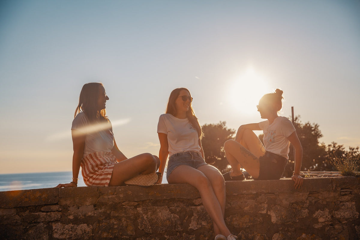 Drei Freundinnen in Pocket Shirts auf einer Steinmauer am Meer in Kroatien