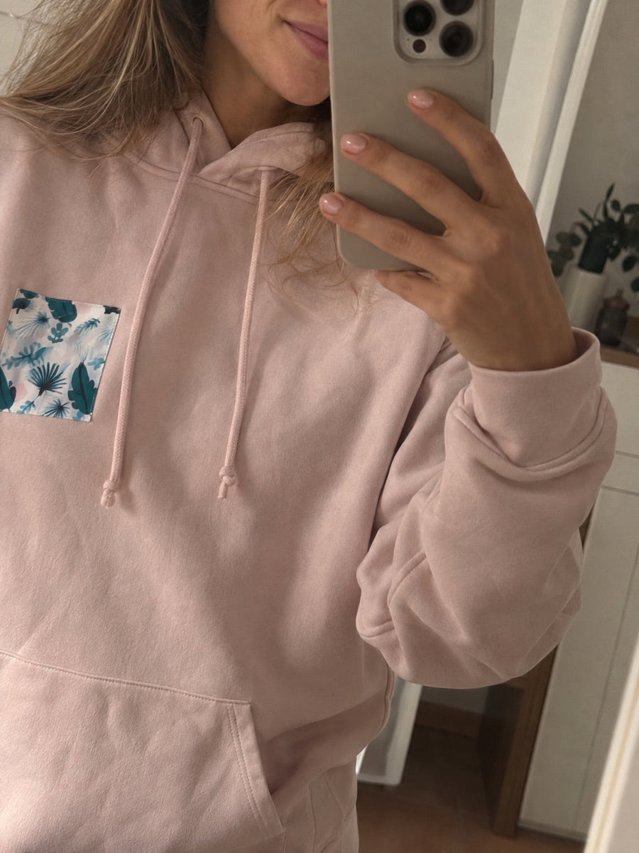 Kundin im rosa Hoodie mit Brusttasche im Blätter-Muster