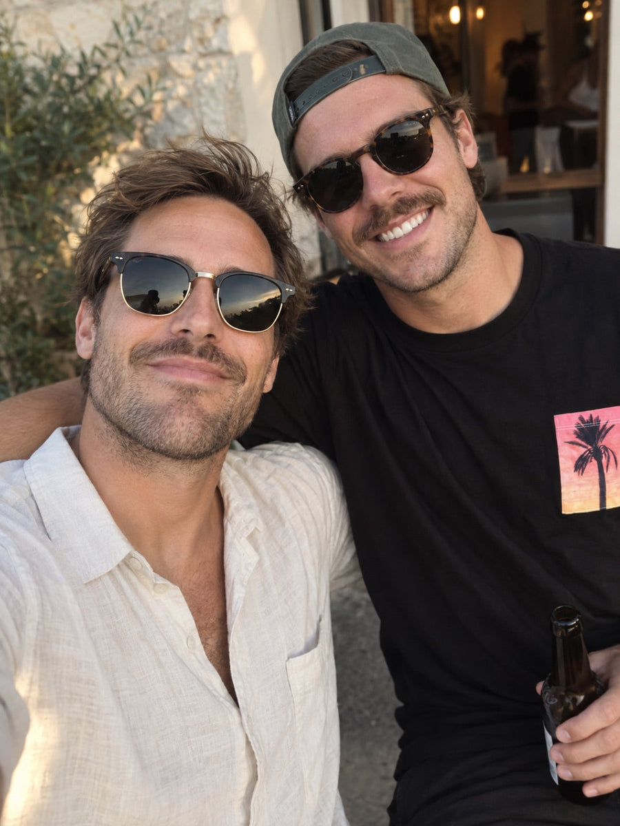 Zwei Freunde im Urlaub, einer trägt ein schwarzes Pocket Shirt mit Palmen-Brusttasche